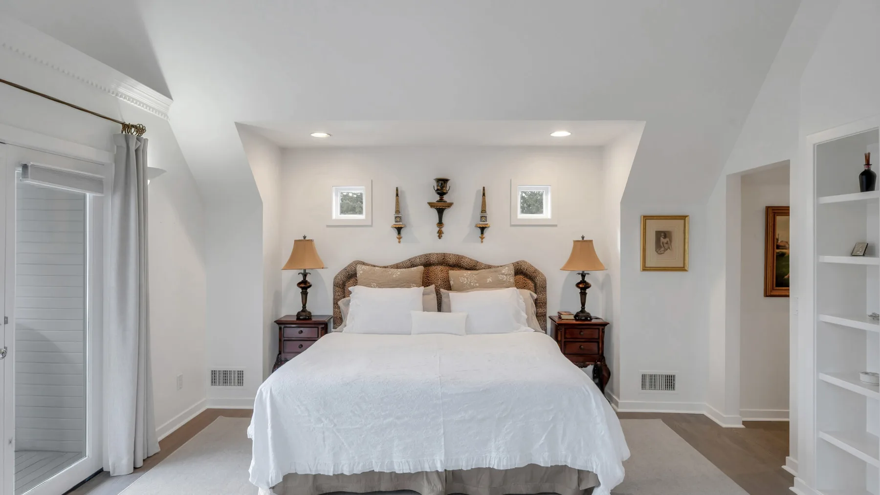 Un dormitorio luminoso con una cama grande entre dos mesitas de noche.