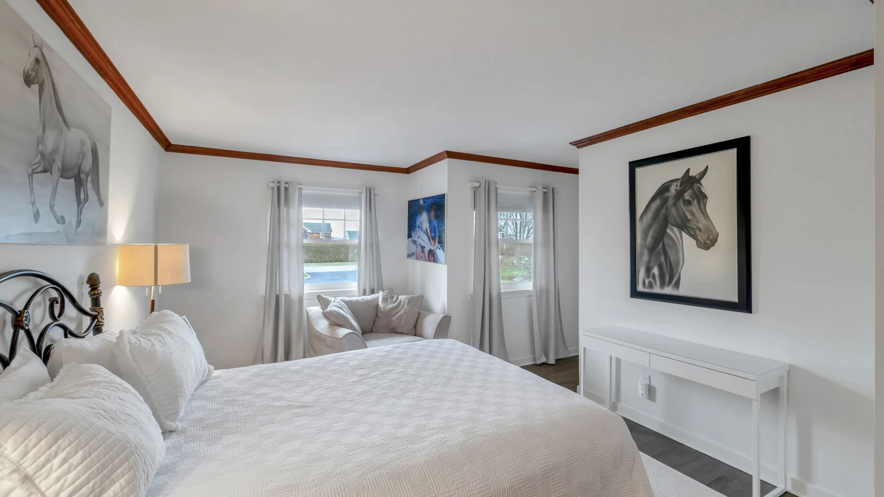 Un dormitorio luminoso con una cama bien arreglada y un cuadro de un caballo.