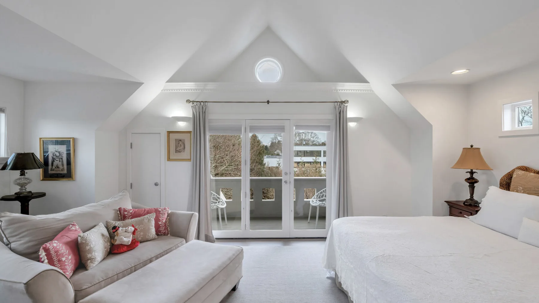 Un dormitorio luminoso con una cama, una zona de estar y puertas de cristal que dan a un patio.