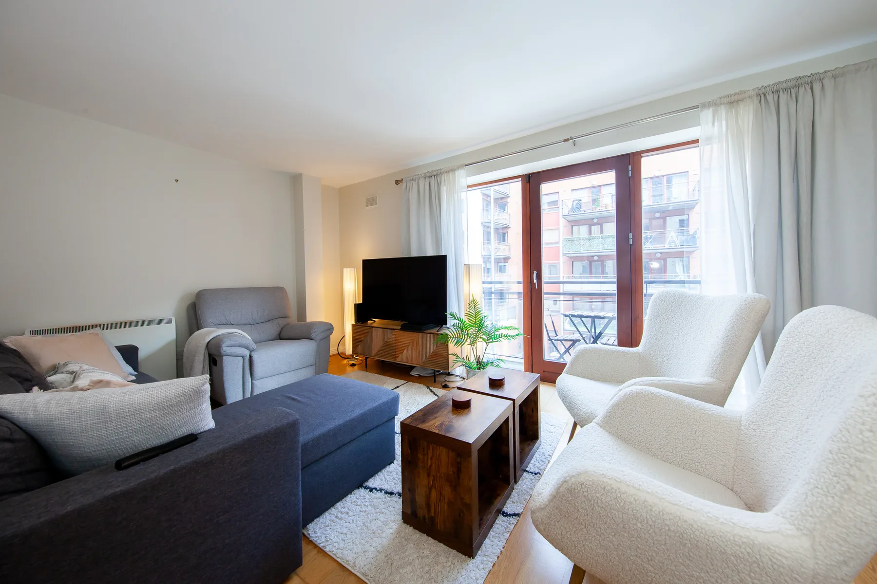 Una sala de estar luminosa con asientos alrededor de una mesa de centro y un televisor.