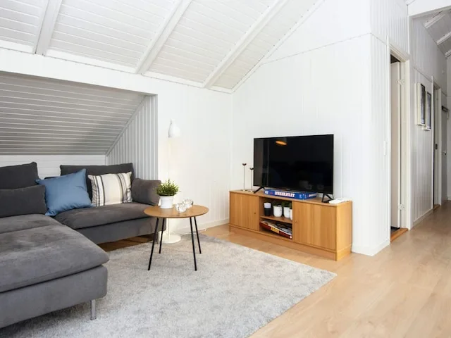 A bright living room with gray seating, a coffee table, and a television.