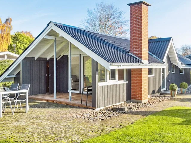 A modern house with a covered patio and outdoor seating beside a lawn.