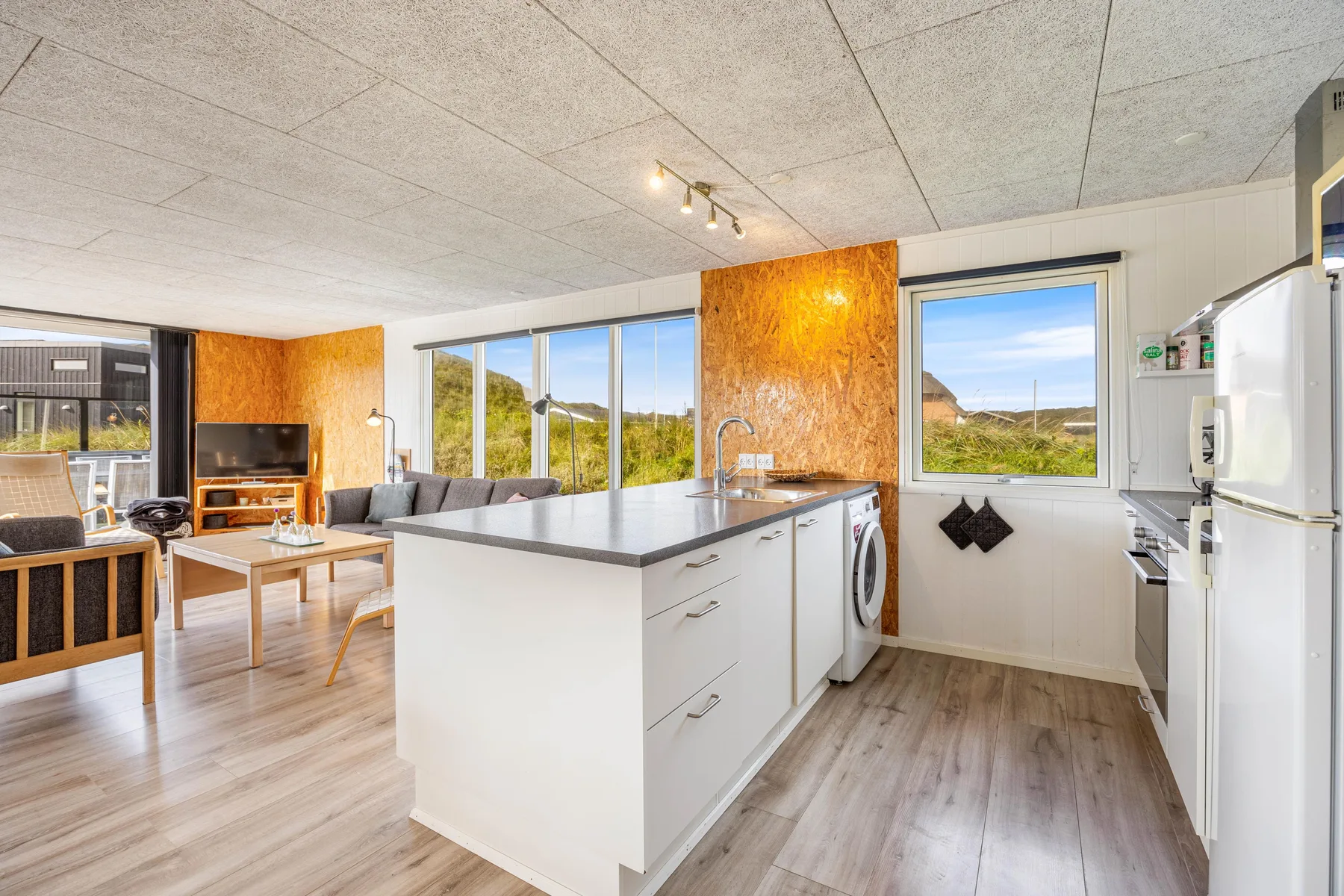 Cocina y sala de estar de planta abierta, con una isla central y ventanas.
