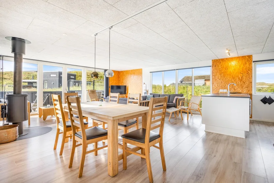Un comedor luminoso con una gran mesa de madera y ventanas con vistas al paisaje.