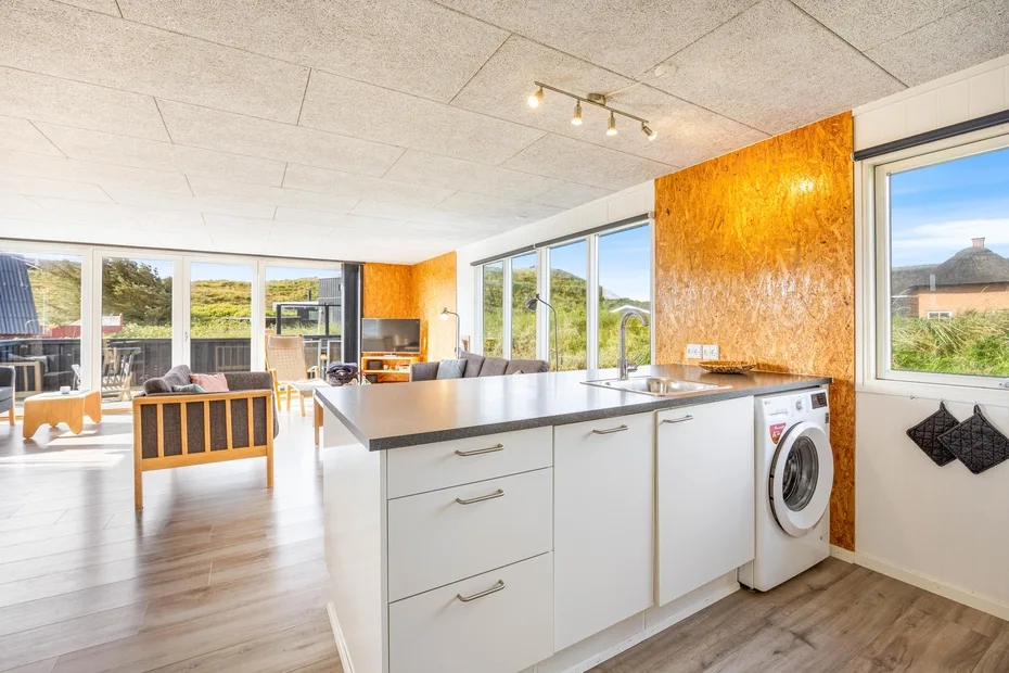 Una cocina abierta y luminosa con una isla central y grandes ventanas.
