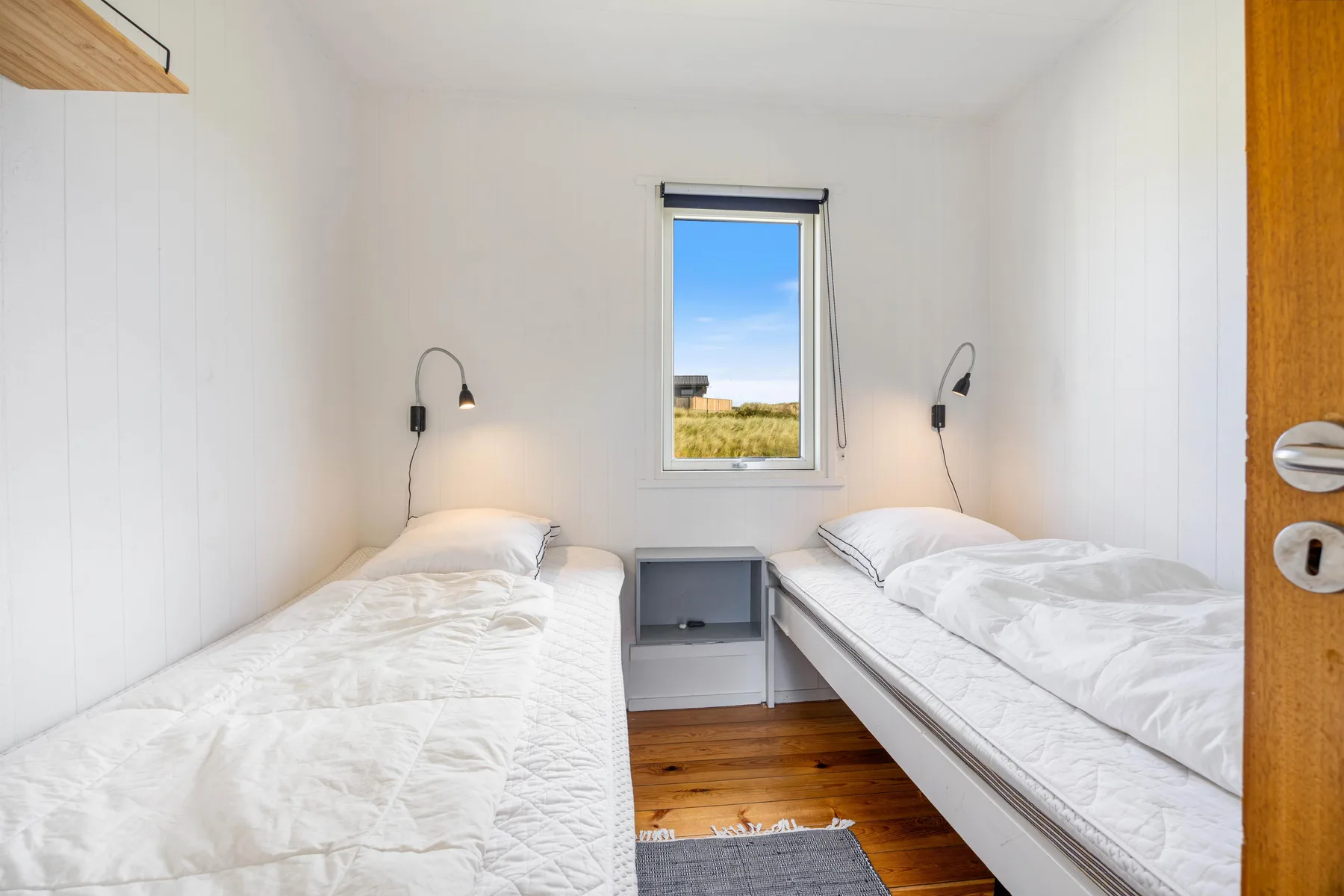 Un dormitorio luminoso con dos camas individuales y una ventana entre ellas.