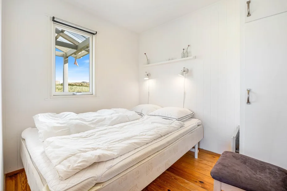 Un dormitorio con una cama, ropa de cama blanca y una ventana con vistas al paisaje.