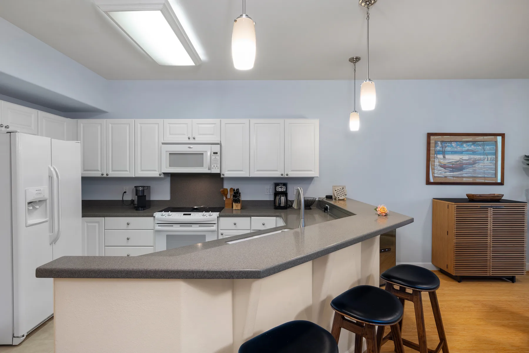 Una cocina con gabinetes blancos y una isla grande con asientos.