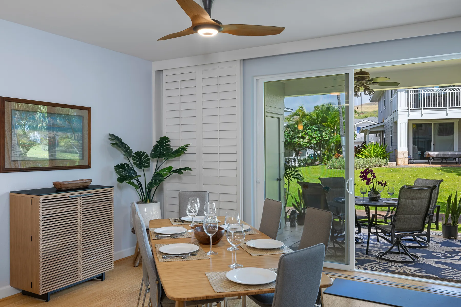Comedor con una mesa junto a puertas corredizas de vidrio que dan a un patio con jardín.