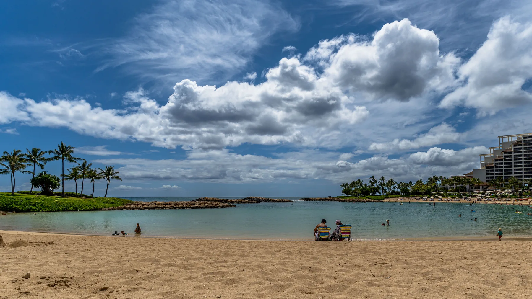 Una playa de arena bordea aguas tranquilas bajo un cielo nublado.