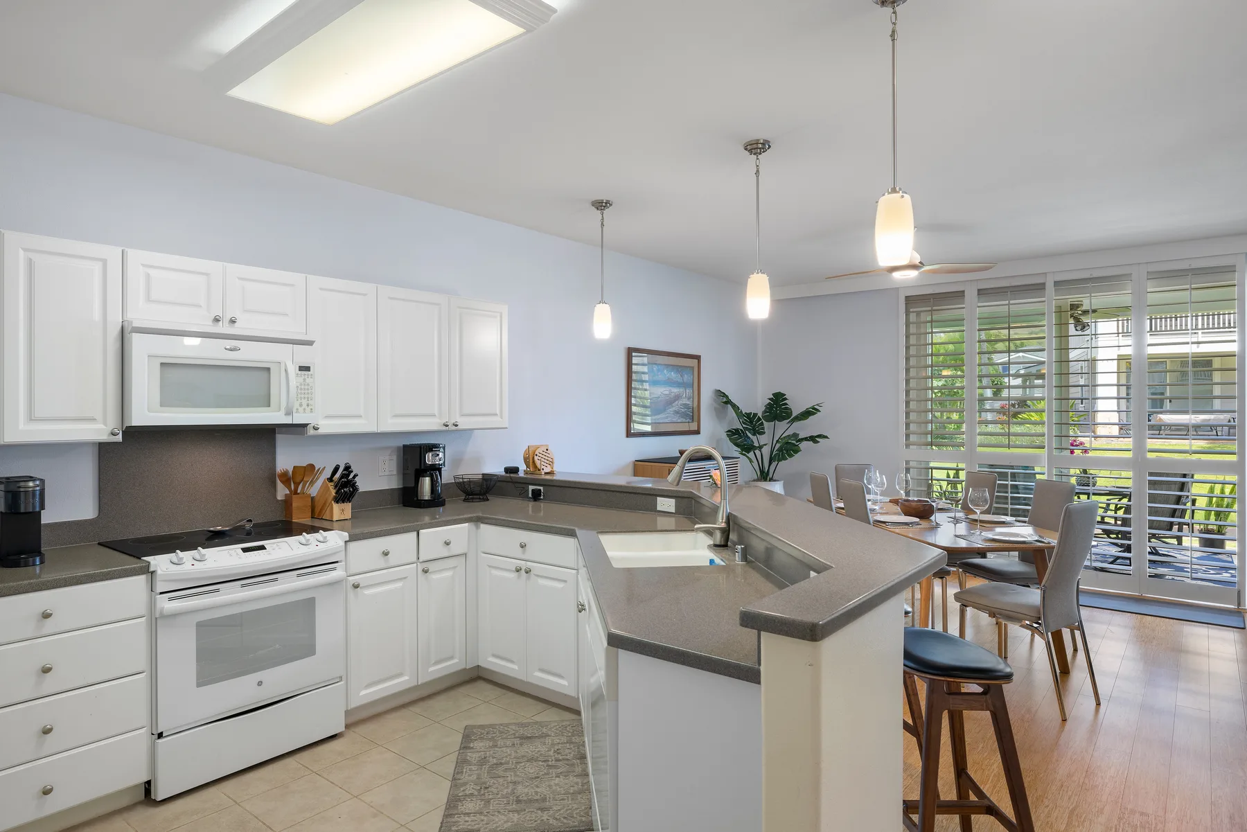 Una cocina luminosa con una isla central se abre a un comedor.