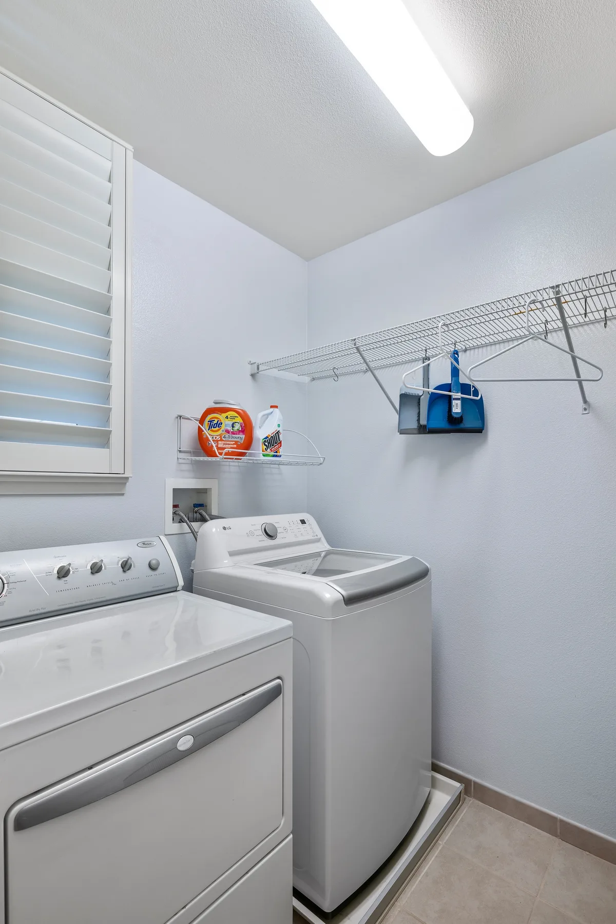 Un cuarto de lavandería con lavadora, secadora y tendedero de pared.