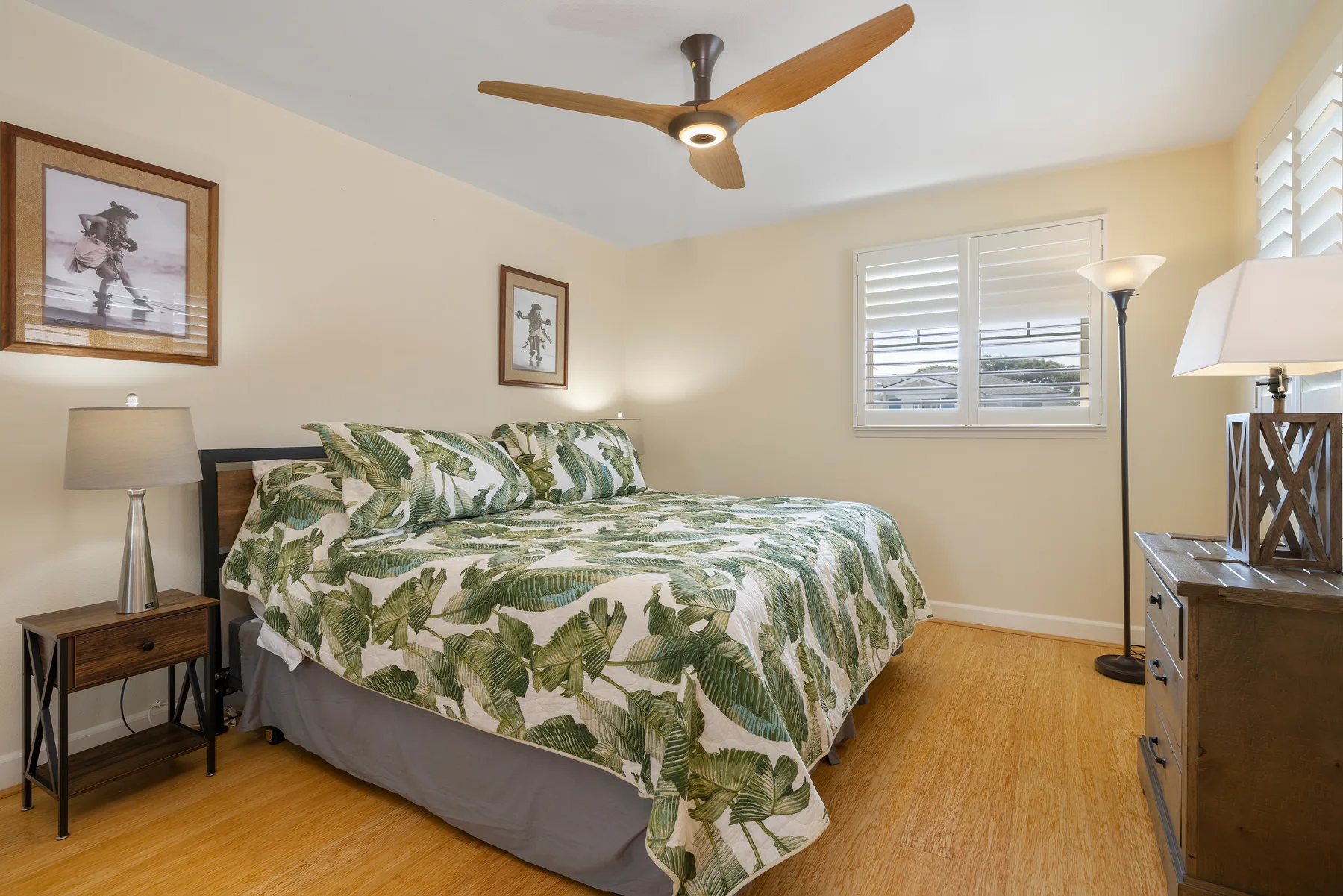 Un dormitorio con una cama cubierta con ropa de cama botánica verde y blanca.