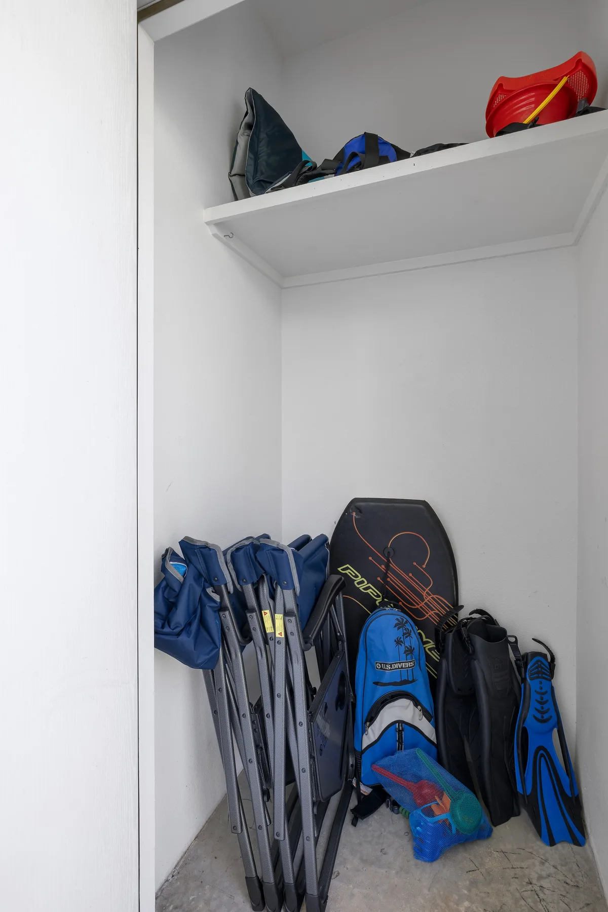 Un armario de almacenamiento contiene sillas plegables, bolsos y equipo para actividades al aire libre.