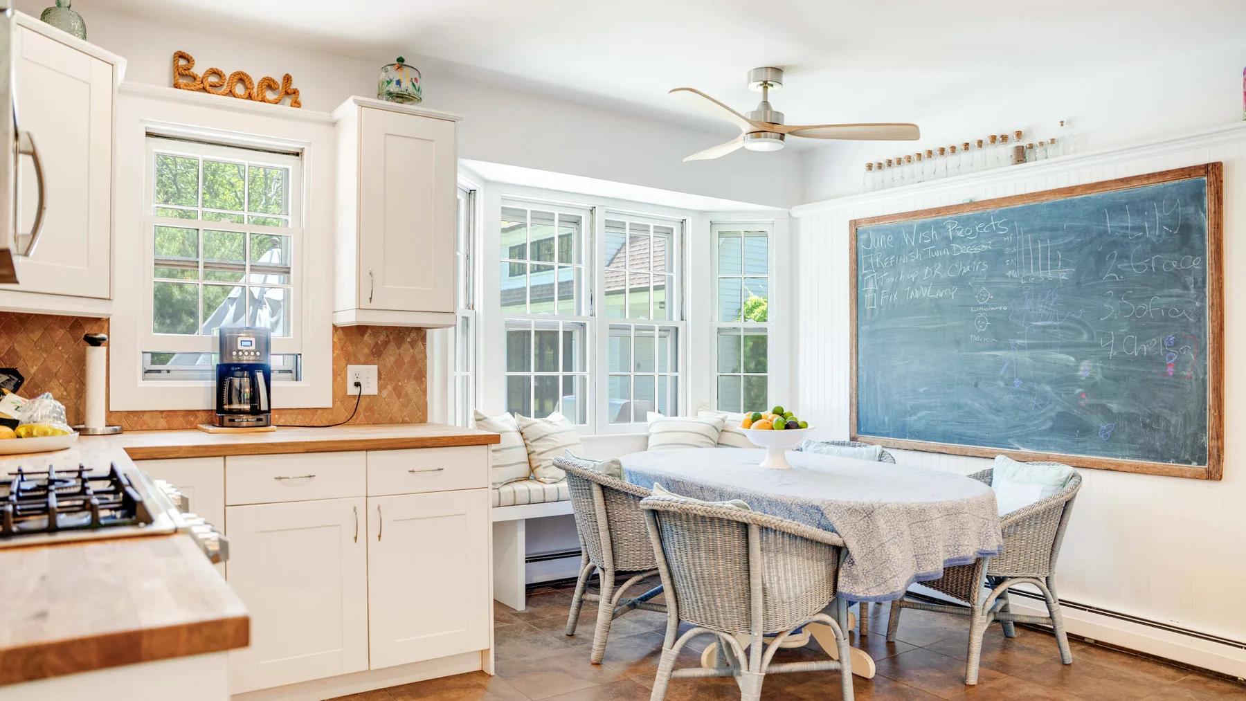 Una luminosa cocina y comedor con una pizarra grande y una mesa.