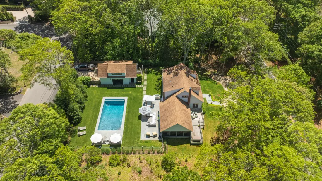 Vista aérea de una casa junto a una piscina, rodeada de árboles.