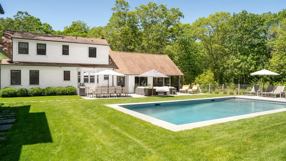 Una casa y una piscina exterior están junto a un césped verde.