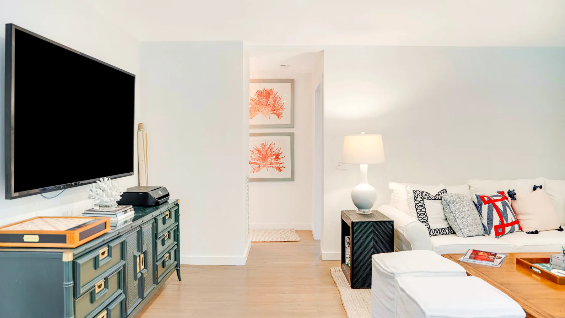 Una sala luminosa con televisor, asientos y cuadros enmarcados.