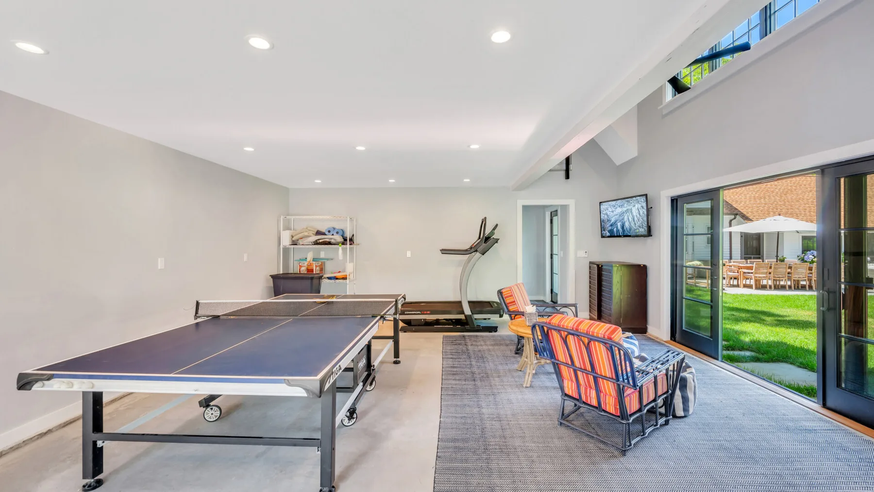 Una sala de recreación con una mesa de ping-pong y asientos junto a puertas de vidrio.