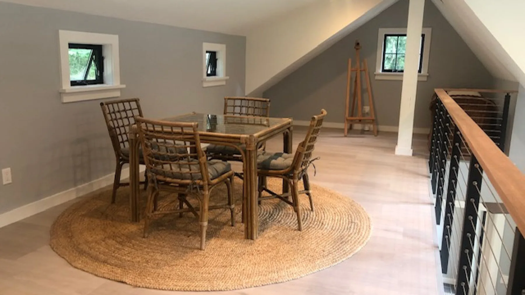 Comedor con una mesa de madera y sillas sobre una alfombra redonda tejida.