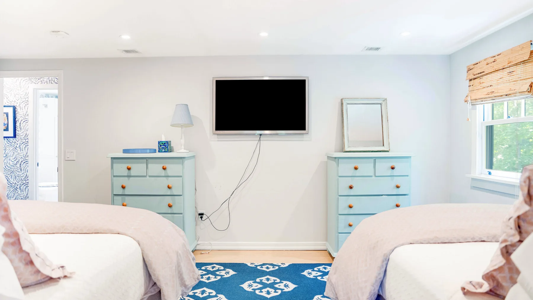Un dormitorio con dos camas y un televisor montado en la pared.