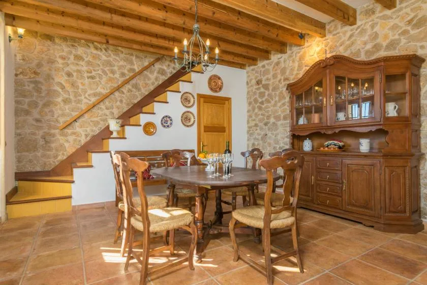 A rustic dining room with a wooden table, chairs, and a large display cabinet.