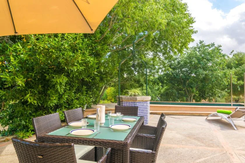An outdoor dining area with a table and seating beneath a large umbrella.
