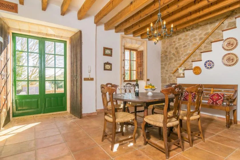 A dining room with a wooden table and chairs beside green double doors.