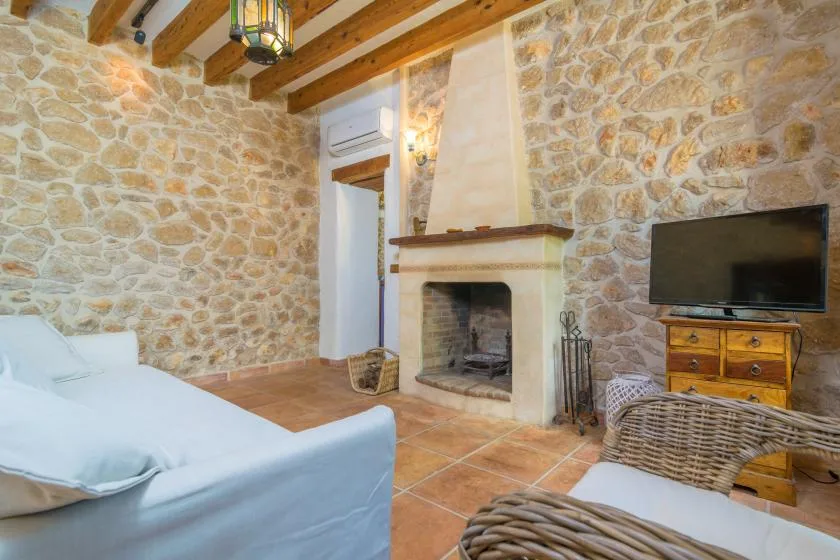 A stone-walled living room with a fireplace, seating, and a television.