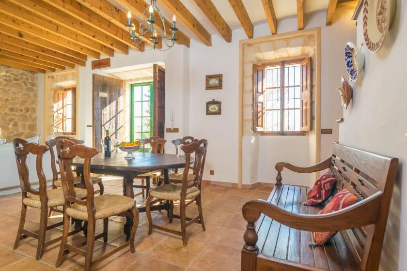 A dining area with a wooden table and chairs beside a carved wooden bench.