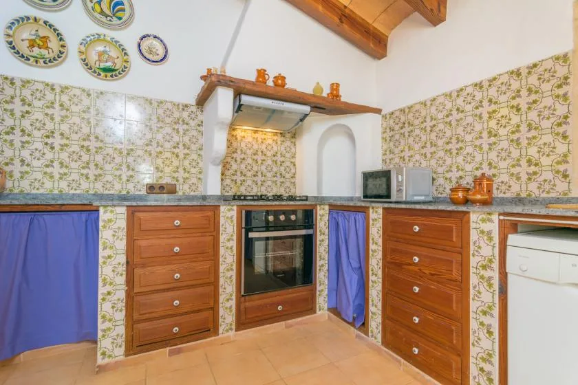 A tiled kitchen with a built-in oven, wooden cabinets, and blue curtains.