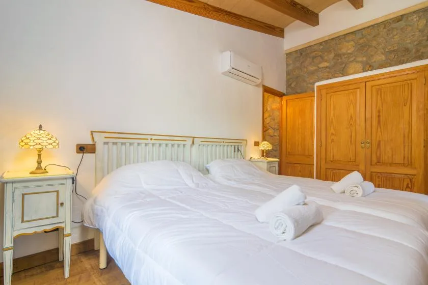 A bedroom with white bedding, bedside tables, and wooden wardrobes.