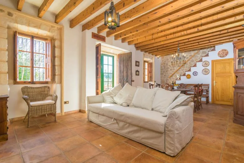 A living room with a white sofa beneath exposed wooden ceiling beams.