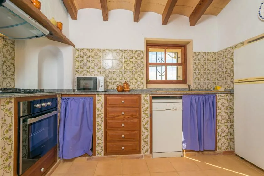 A kitchen with a tiled backsplash, wooden cabinets, and a small window.