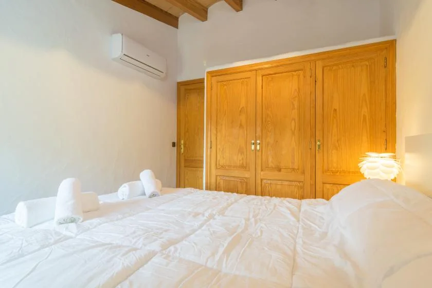 A bedroom with white bedding and wooden wardrobes.