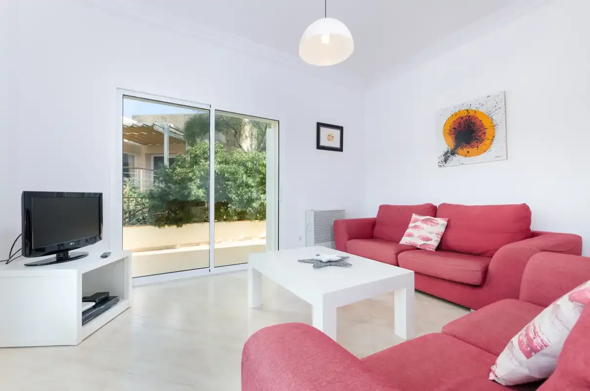 Una sala de estar luminosa con asientos rosas y una mesa de centro blanca.
