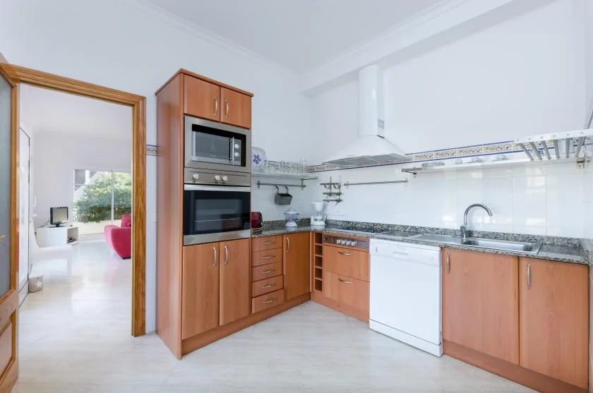 Una cocina luminosa con gabinetes de madera, un horno empotrado y un lavavajillas.