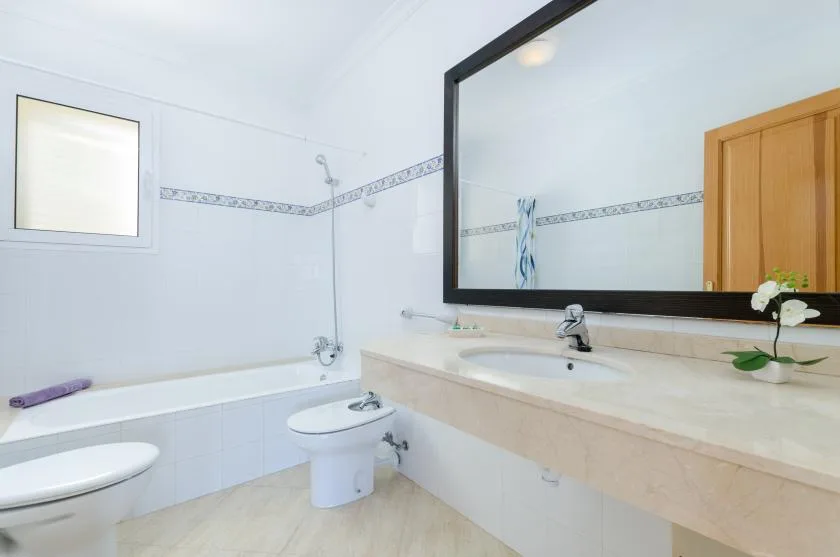 Un baño luminoso con bañera, inodoro y una amplia encimera de lavabo.