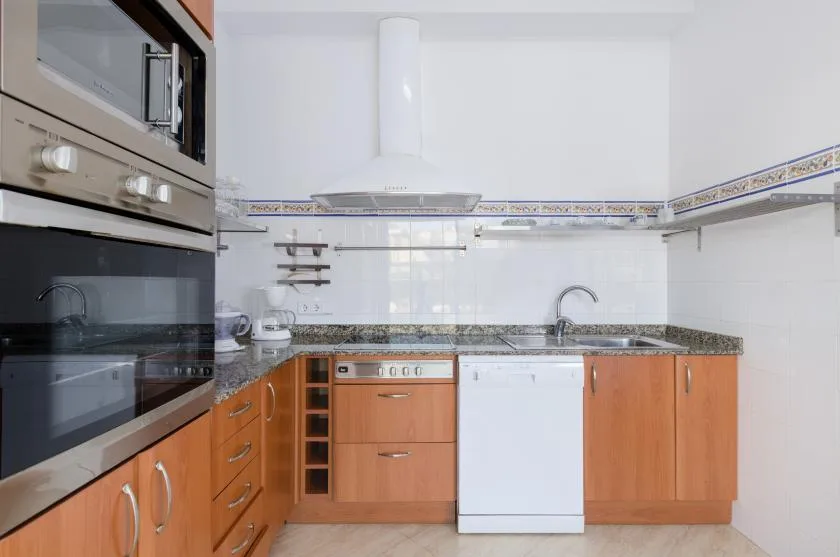 Una cocina luminosa con armarios de madera, una encimera y un fregadero.