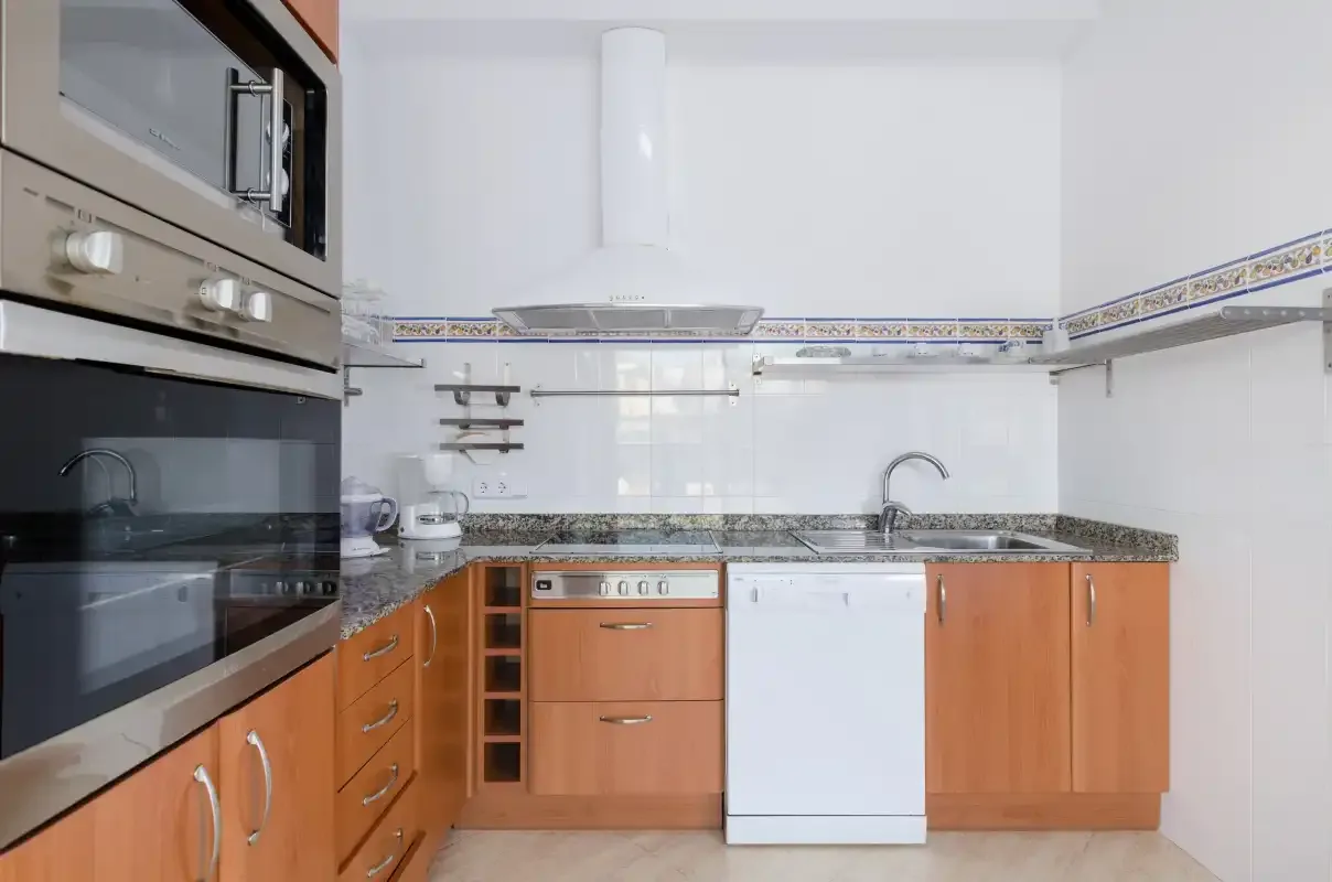 Una cocina luminosa con armarios de tono madera, una encimera y un fregadero.