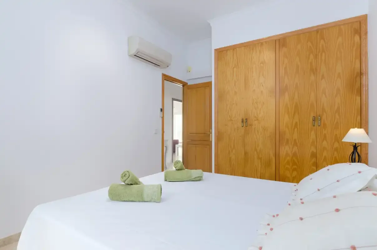 Un dormitorio con una cama blanca y armarios de madera.
