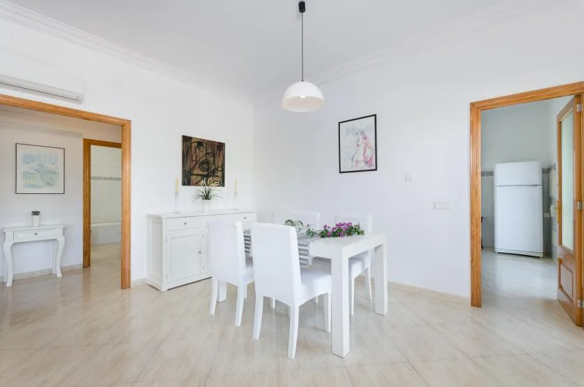 Un comedor luminoso con una mesa blanca y sillas.