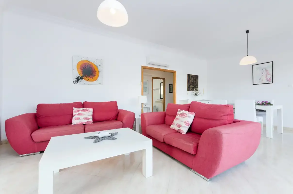Una sala de estar luminosa con asientos rosas y una mesa de centro blanca.