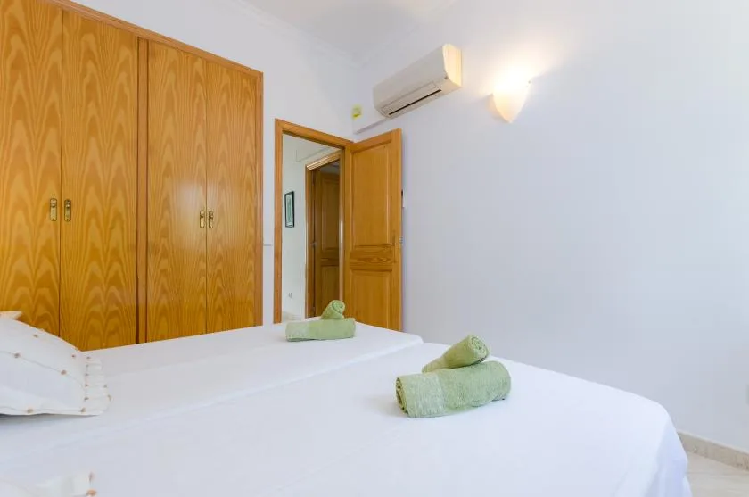 Un dormitorio con camas blancas, armarios de madera y una puerta abierta.