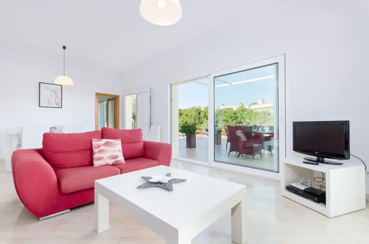 Una sala luminosa con asientos rojos y puertas de vidrio que dan a un patio.