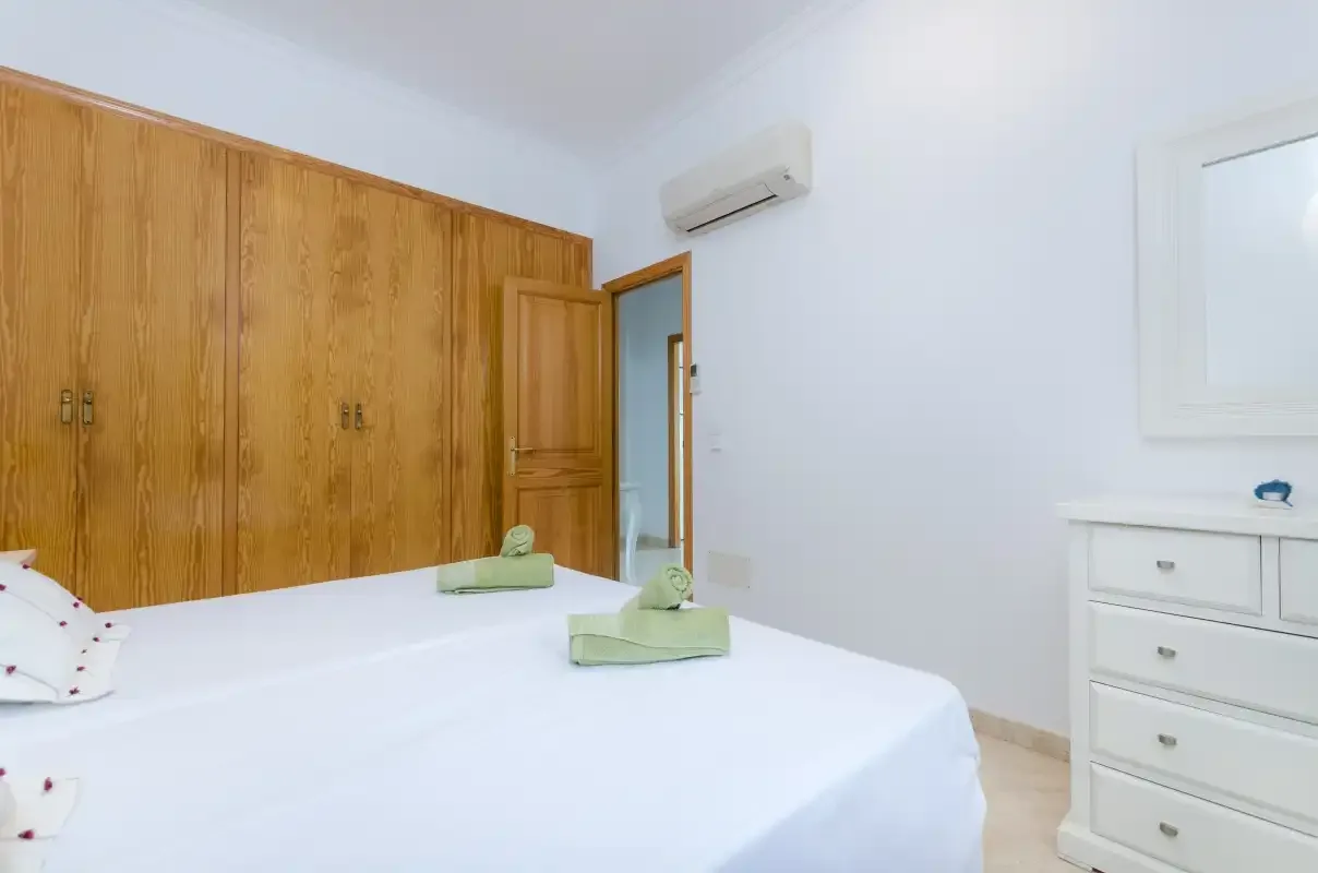 Un dormitorio con una cama bien hecha y armarios de madera.