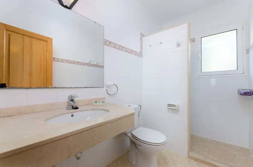 Un baño luminoso con un tocador largo, espejo e inodoro.