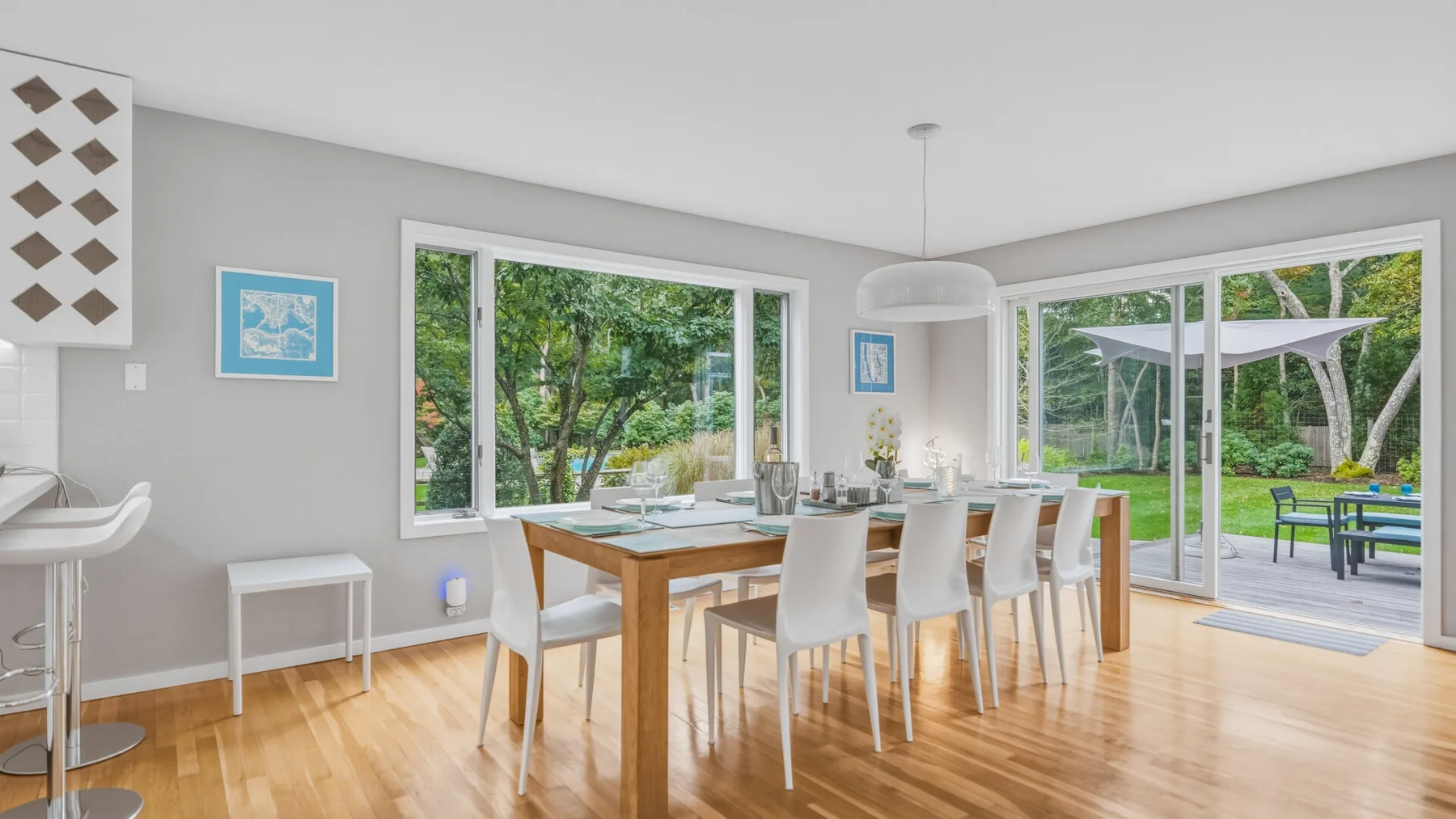 A bright dining area with a long table and garden views through large windows.