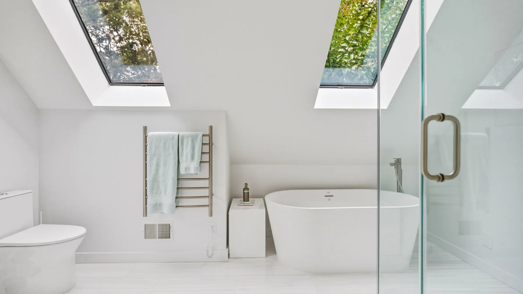 A bright bathroom features a freestanding bathtub beneath skylights.