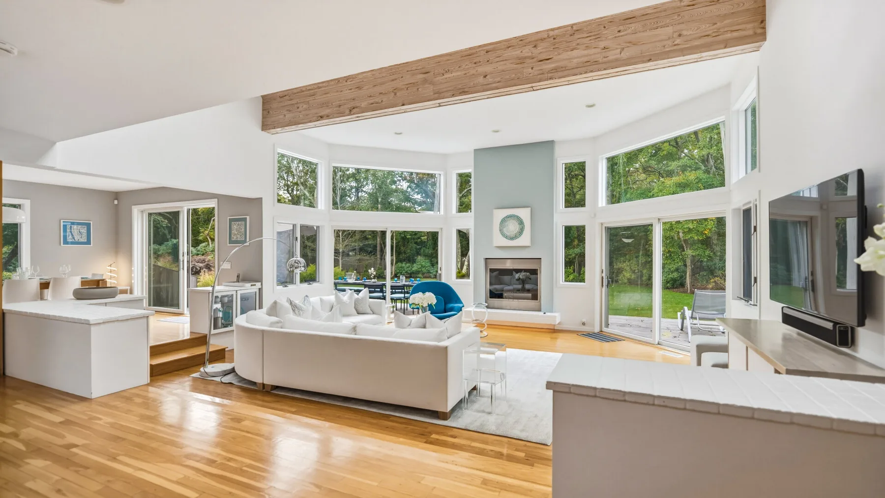 A bright living room with seating, large windows, and a fireplace.